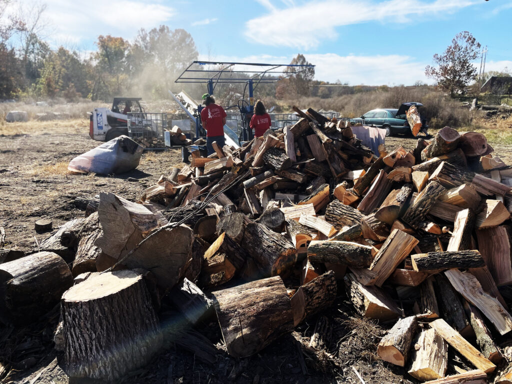 Two employees splitting logs and making piles of firewood